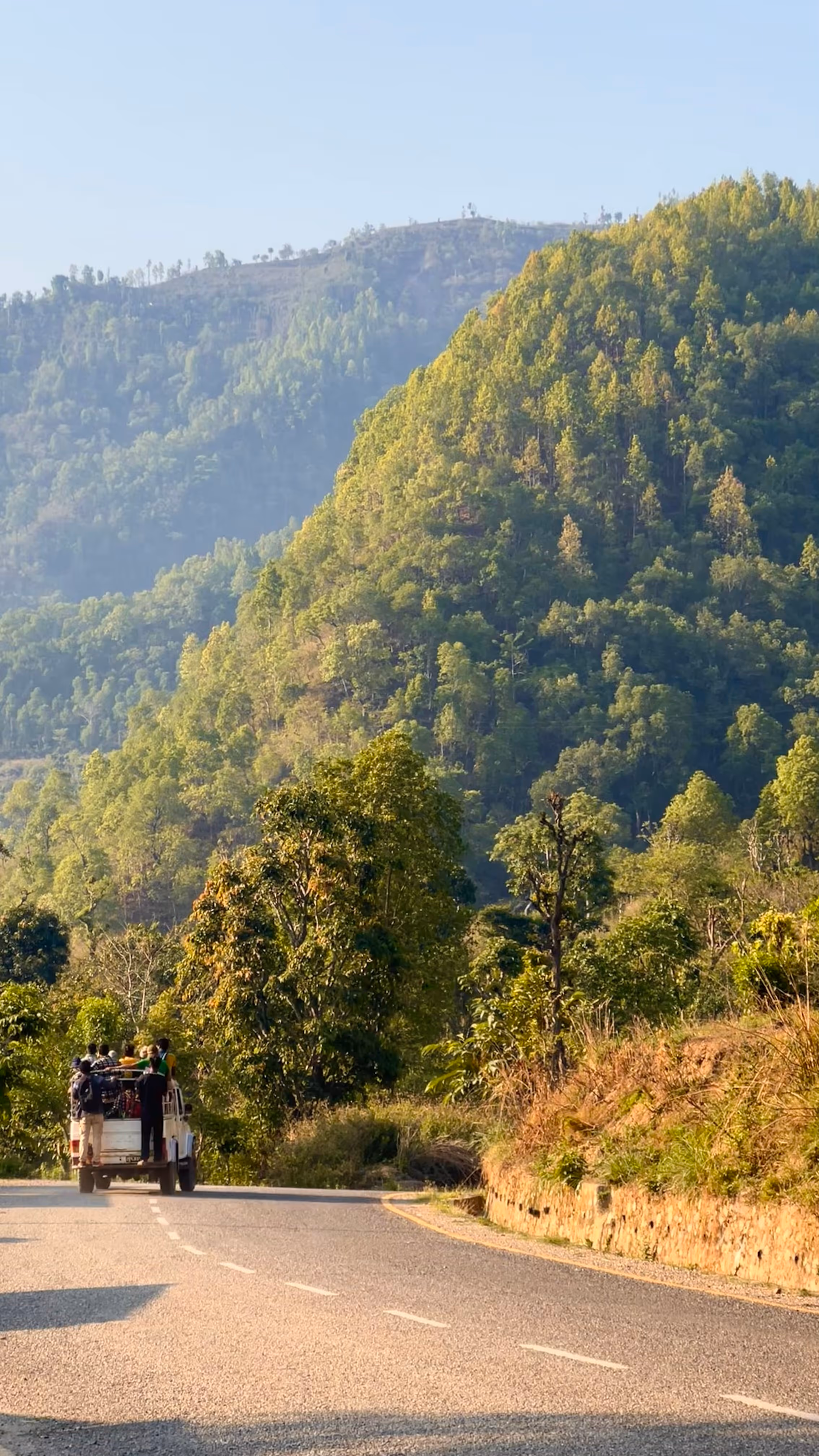 Hilly landscape with a car packed full of people in the distance